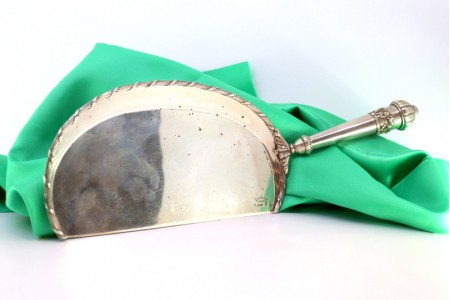 Apanha migalhas em prata com relevos florais e laços no cabo.